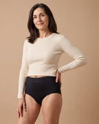 Donna con lo slip assorbente LEIDRY™ Giorno nero a vita alta e maglia color panna