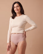 Donna con lo slip assorbente LEIDRY™ Giorno rosa a vita alta e maglia color panna