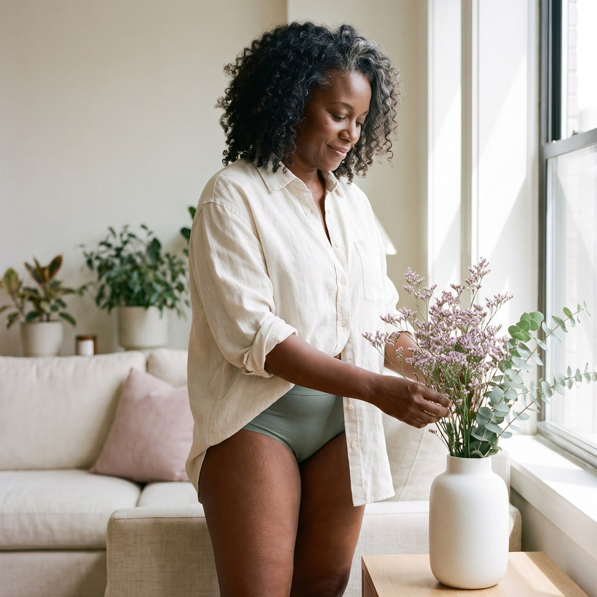 Donna con lo slip assorbente LEIDRY™ Giorno verde salvia a vita alta e maglia color panna