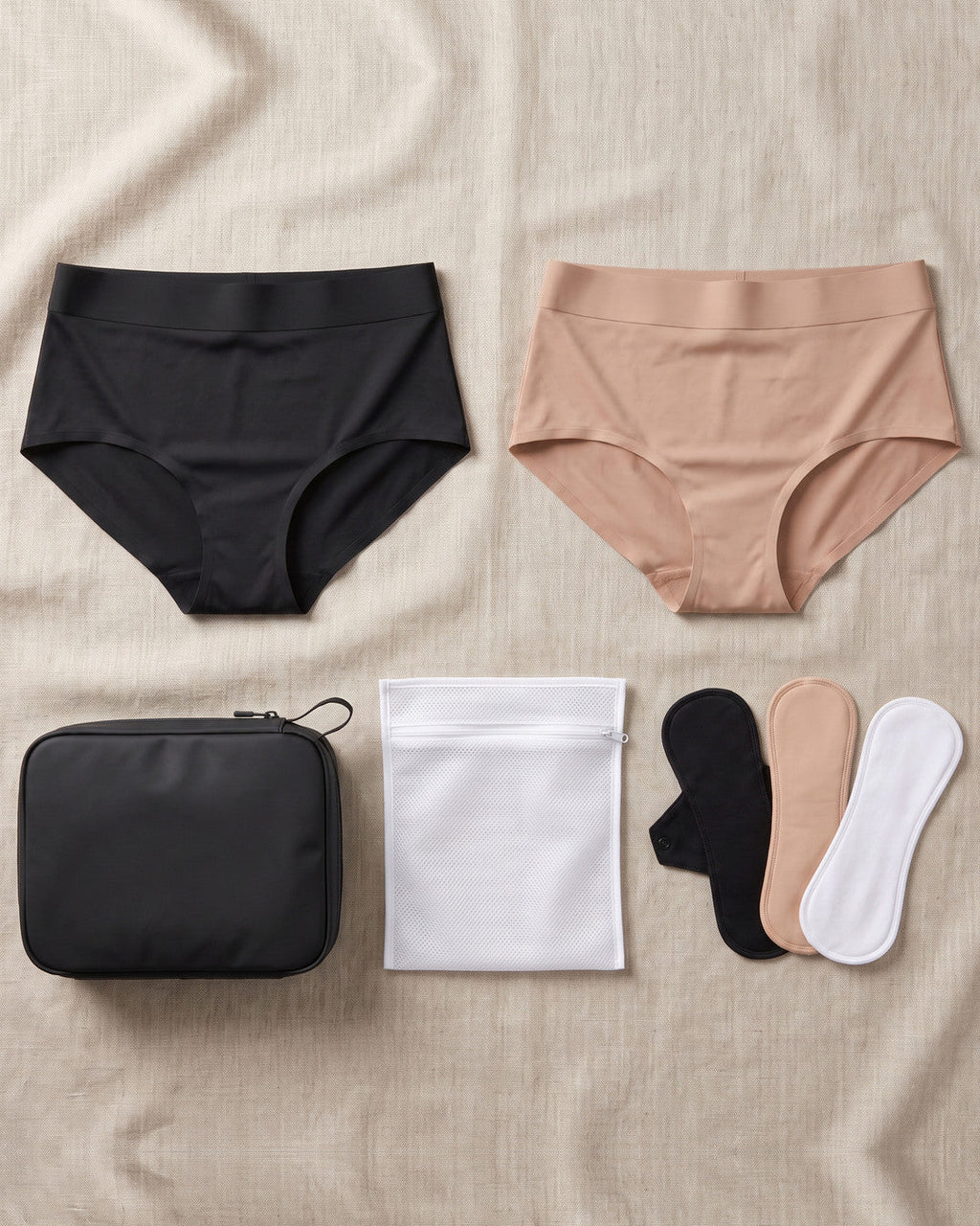 Il kit LEIDRY™ visto dall’alto su lino: due slip, pochette da viaggio, sacca per il lavaggio e salvaslip lavabili
